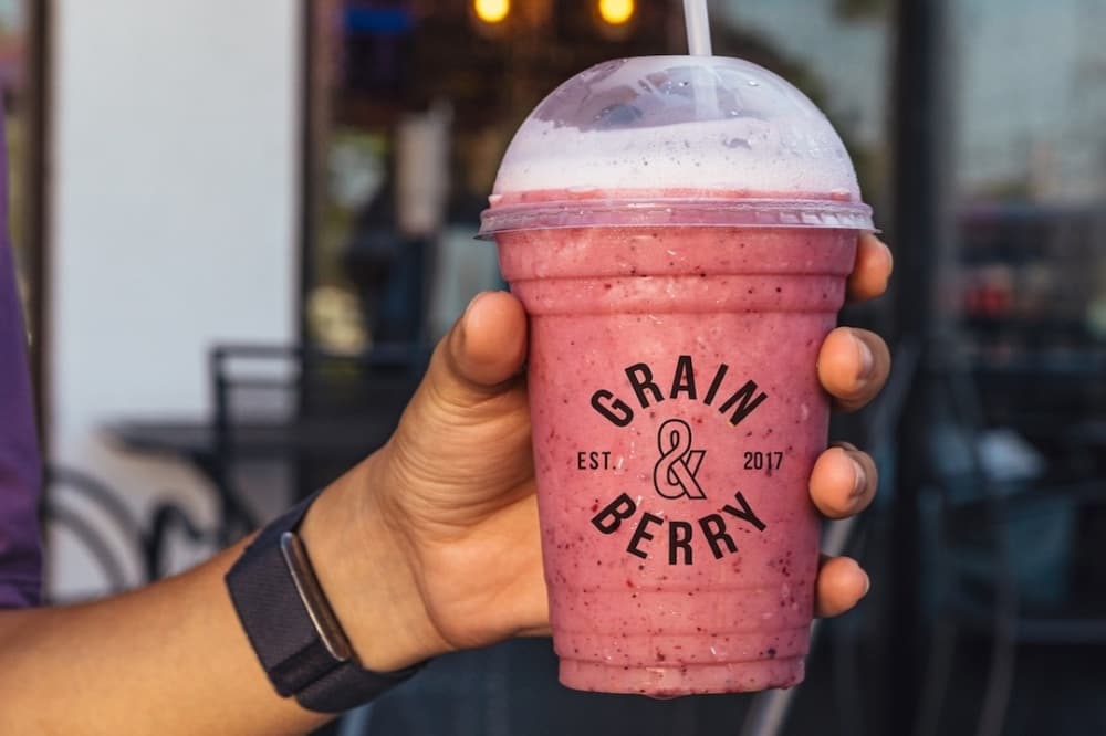 a person holds a pink smoothie