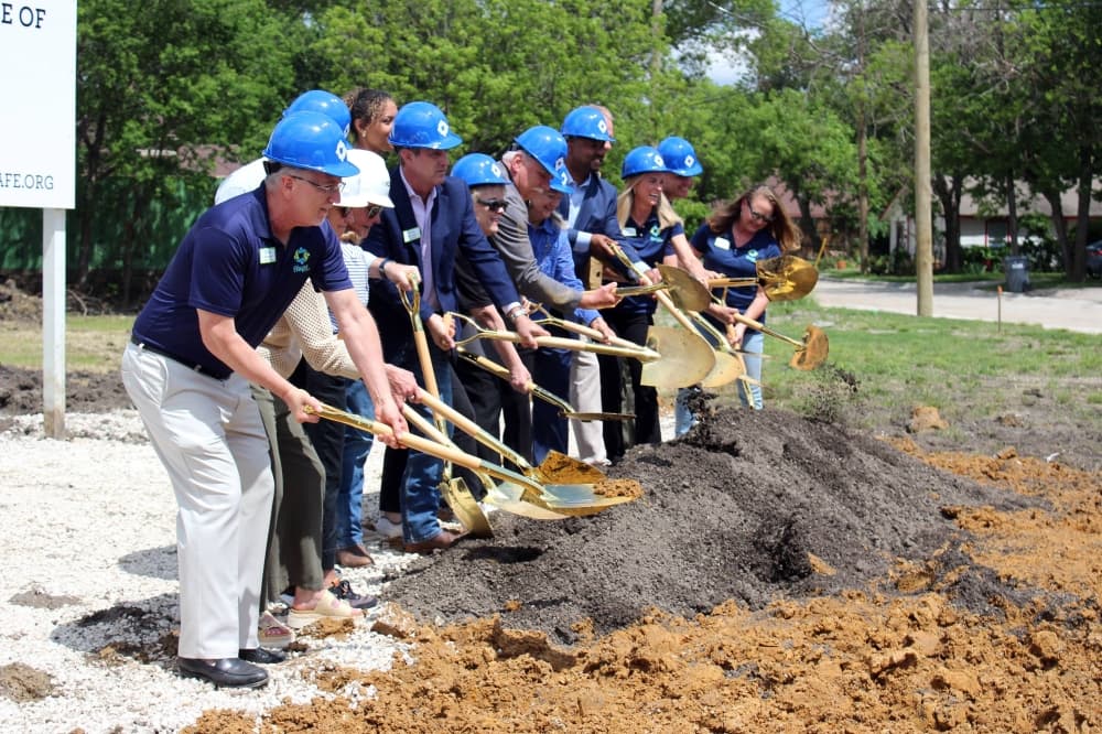 Group of males and females shoveling dirt for a photo opp. 