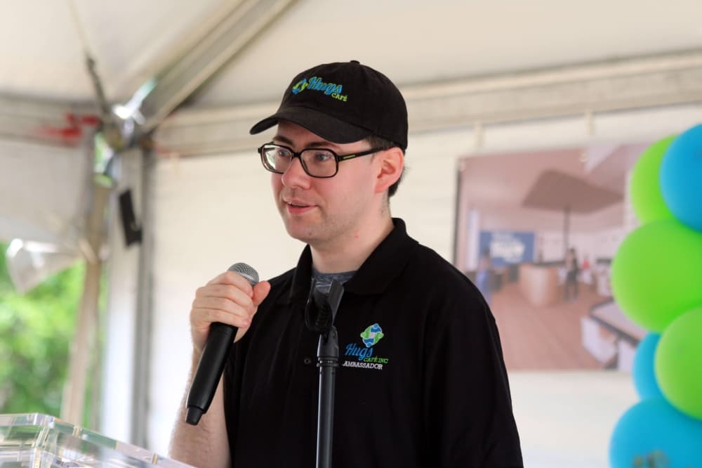 Male speaking into a microphone at a podium. 