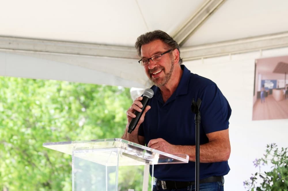 Male speaking into a microphone at a podium. 