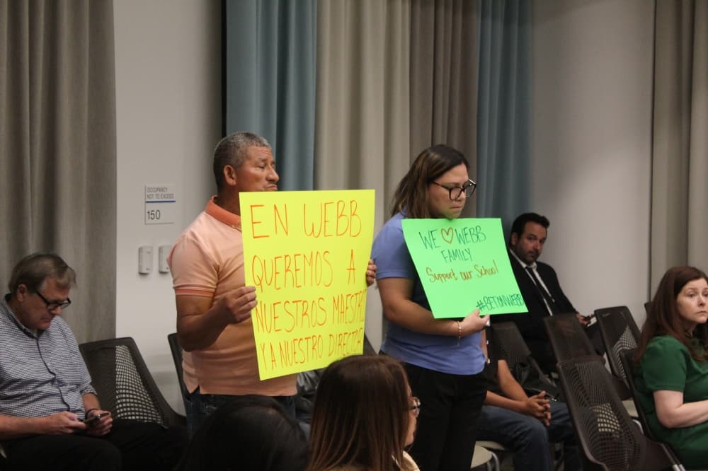Two people hold signs about Webb Middle School