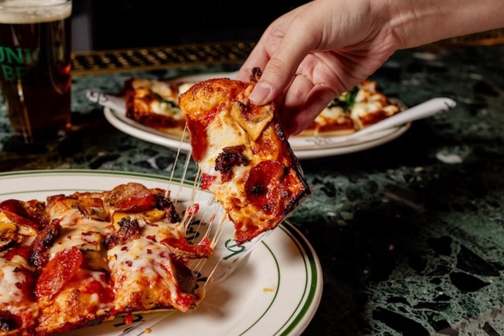 Hand holding pizza