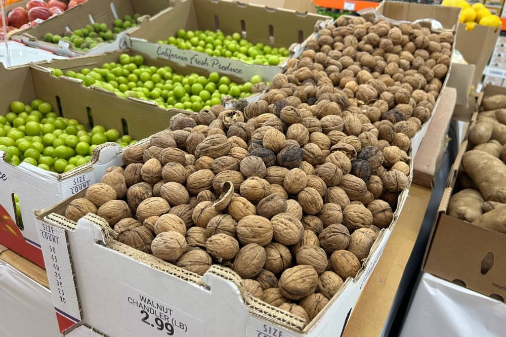 Bins of walnuts next to bins of liimes. 