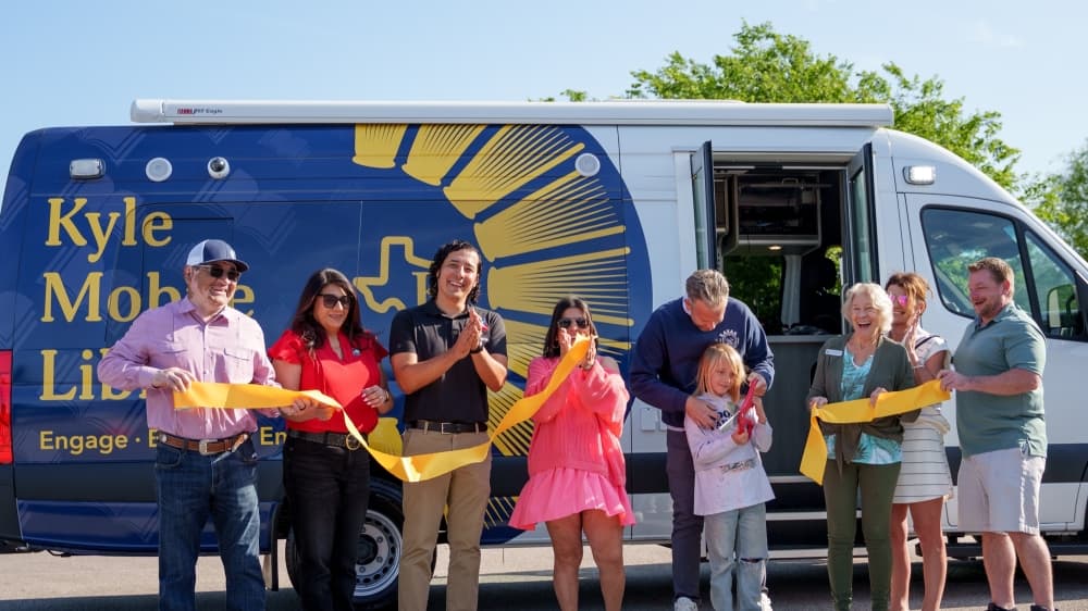 People standing in front of the mobile library cutting a ribbon