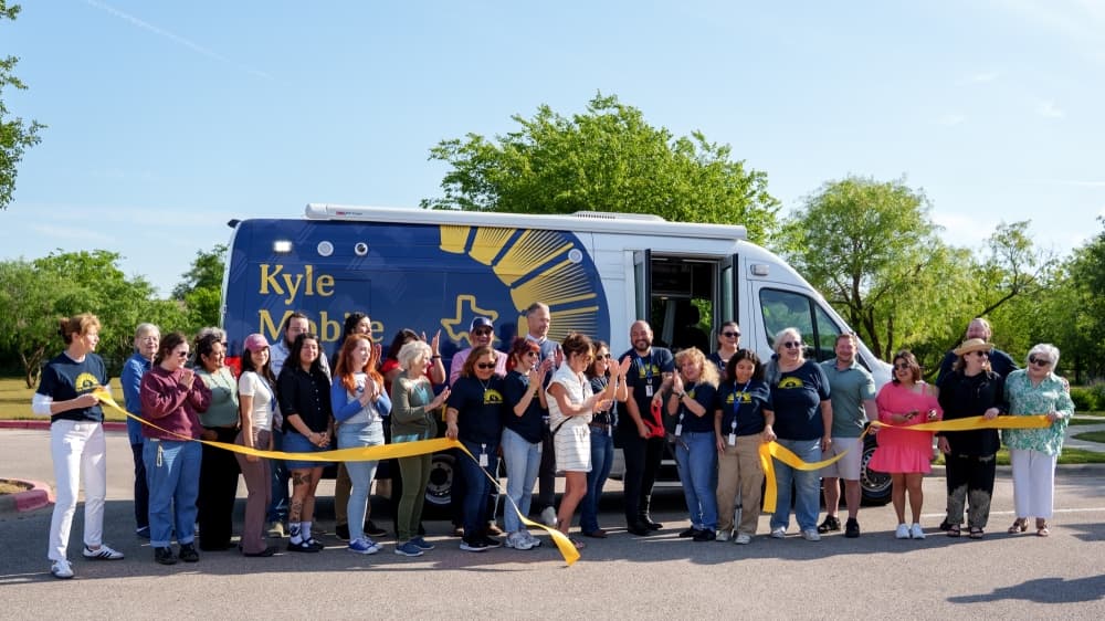 People standing in front of the mobile library cutting a ribbon