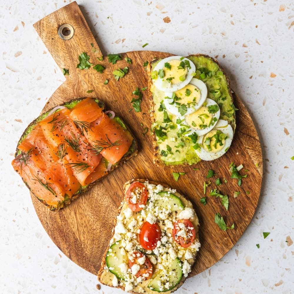 Toasts on a cutting board with salmon, avocado and eggs