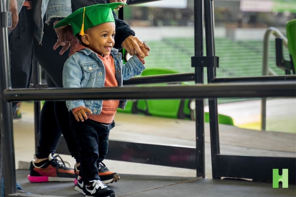 An image of a small child walking in a graduate cap. 