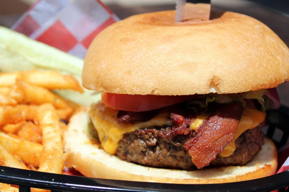 Cheeseburger in a basket with a side of fries. 