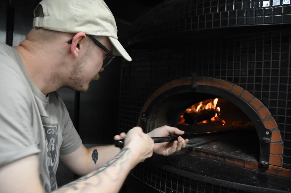 Man works a pizza oven. 