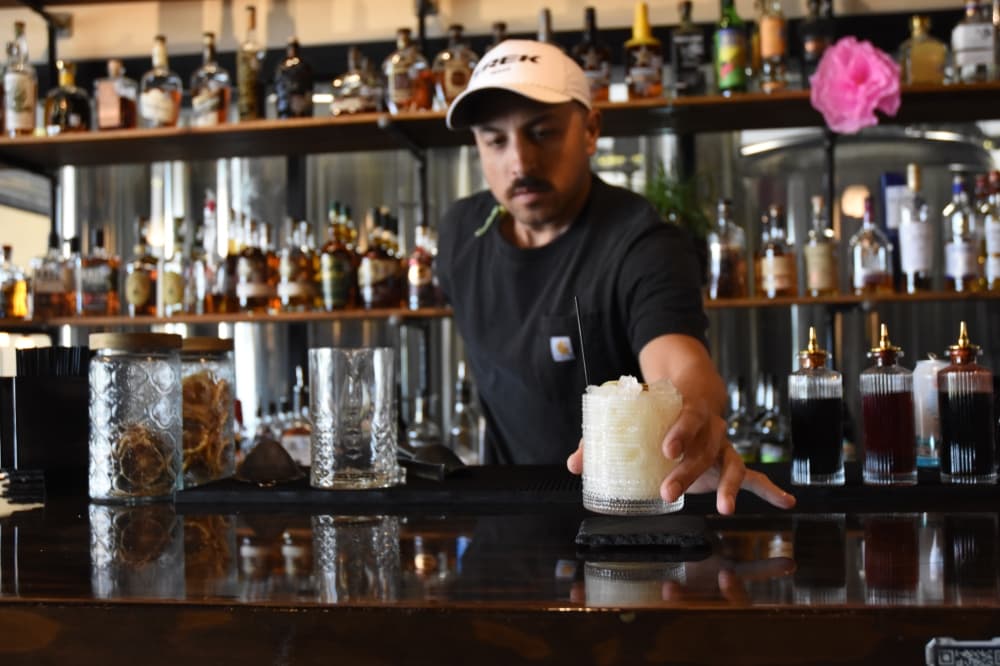 Man serves a drink at a bar. 