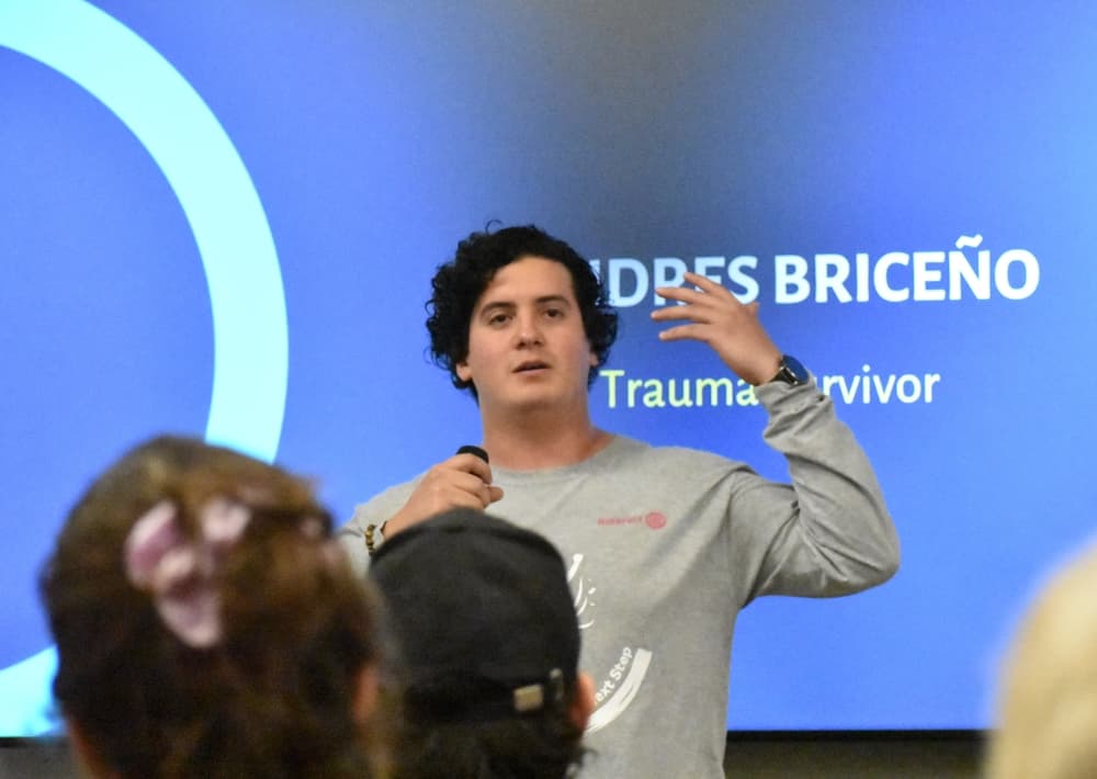 young man speaks in front of a screen