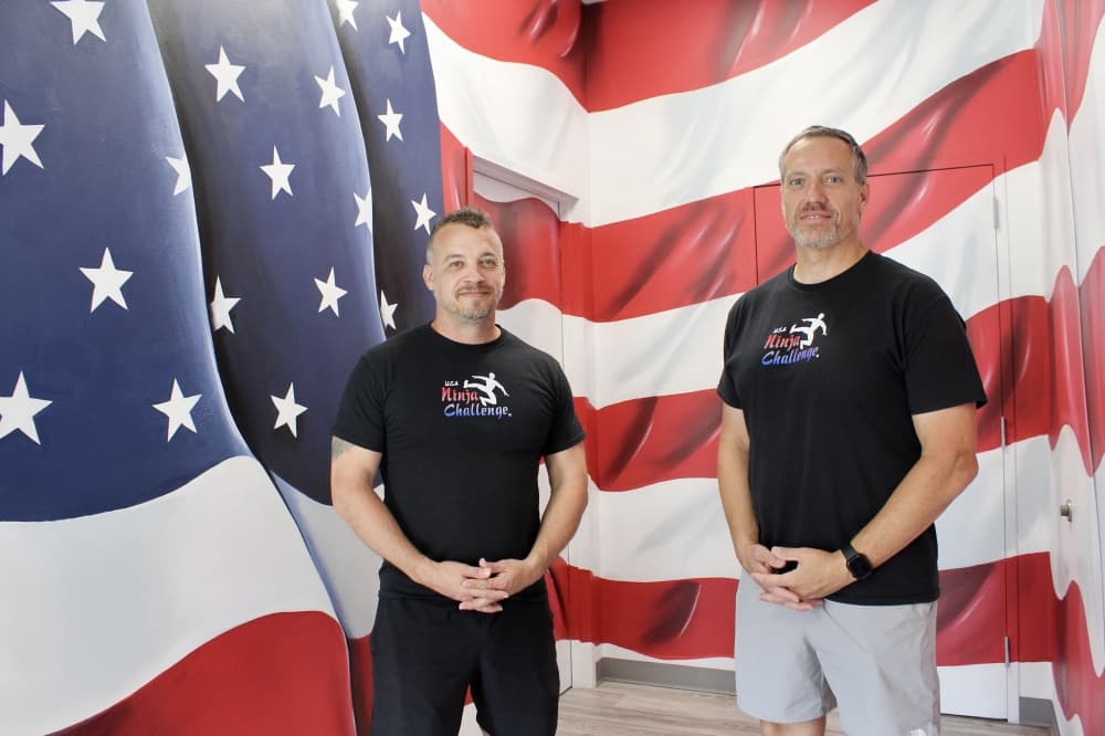 men post in front of a flag