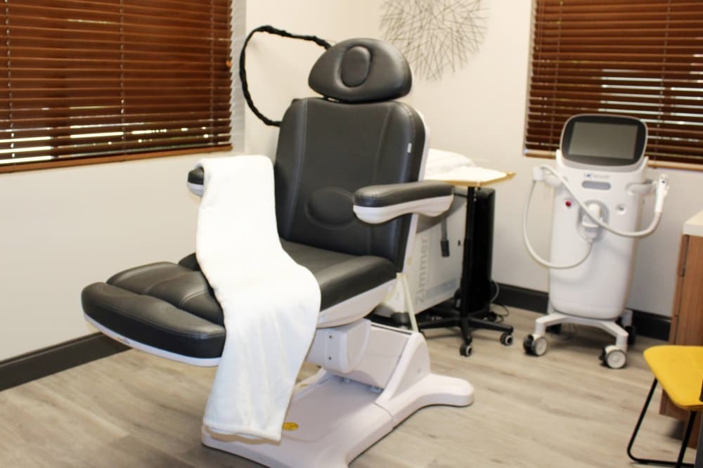 Medical procedure room with medical examination chair draped with a folded white blanket. 