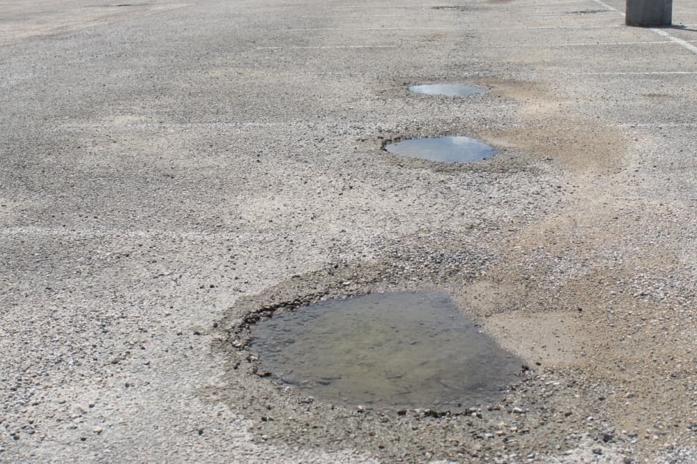 Three large potholes in Clark Stadium's parking lot. 
