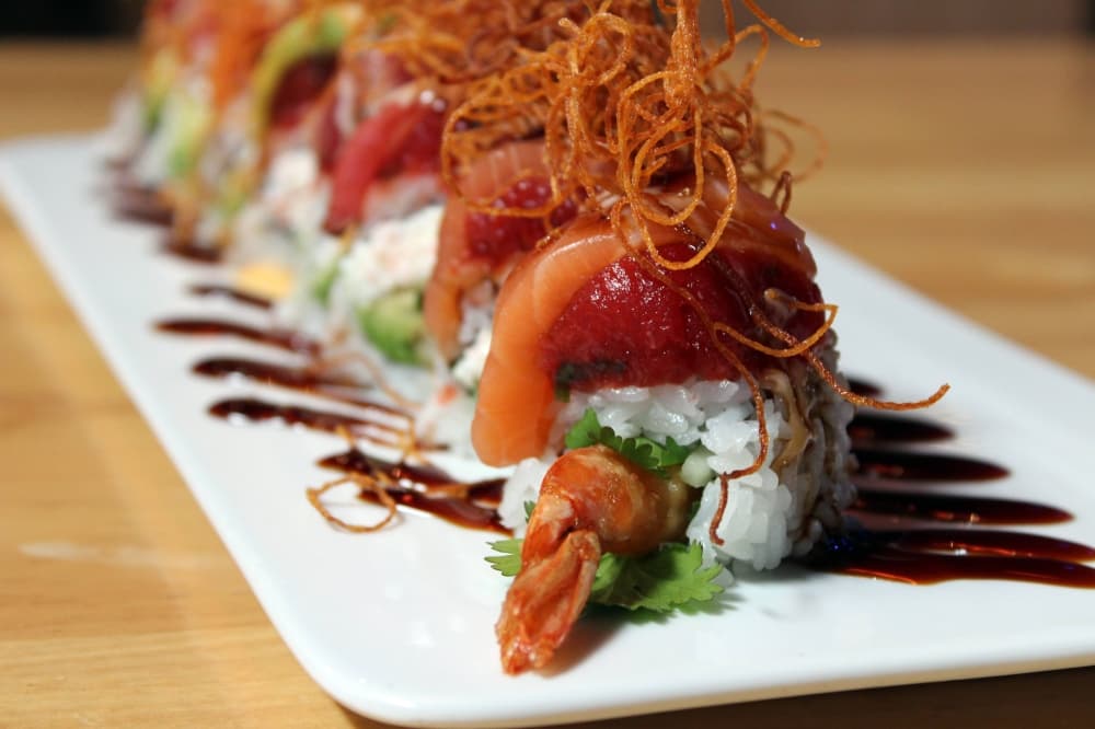 Sushi roll with sashimi and fried sweet potato strings.
