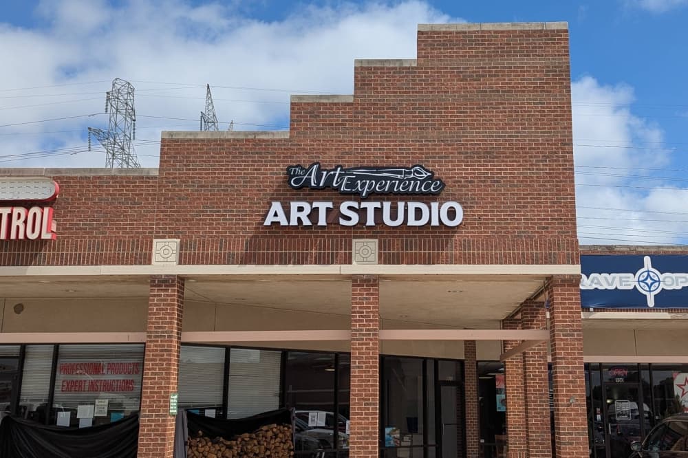 Exterior of a strip mall with The Art Experience Art Studio signage. 