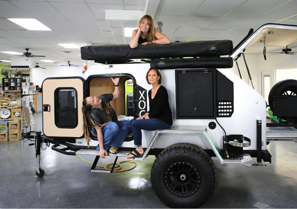 An image of some of the team members and owner of the business with a camper. 