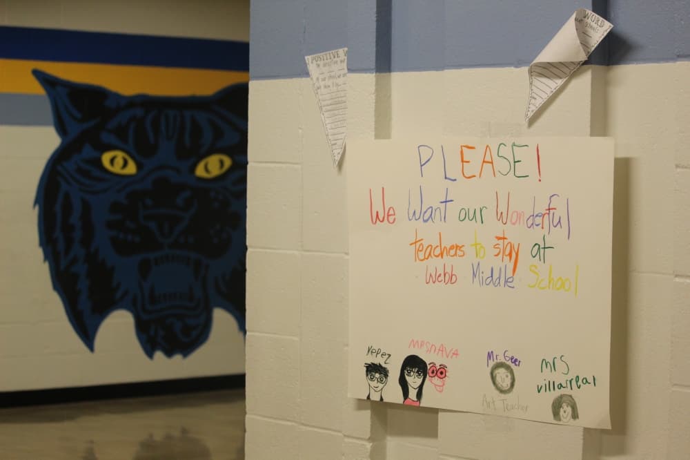 A signs on the wall reads "Please! We want our wonderful teachers to stay at Webb Middle School"