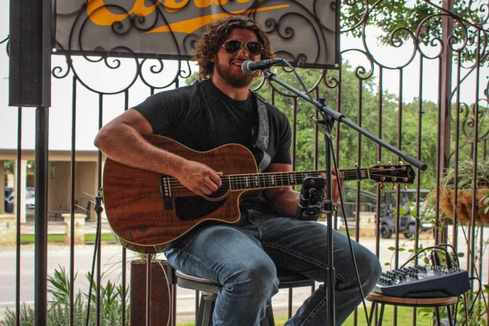 A solo artist strums his guitar and sings soulful vocals to the crowd.