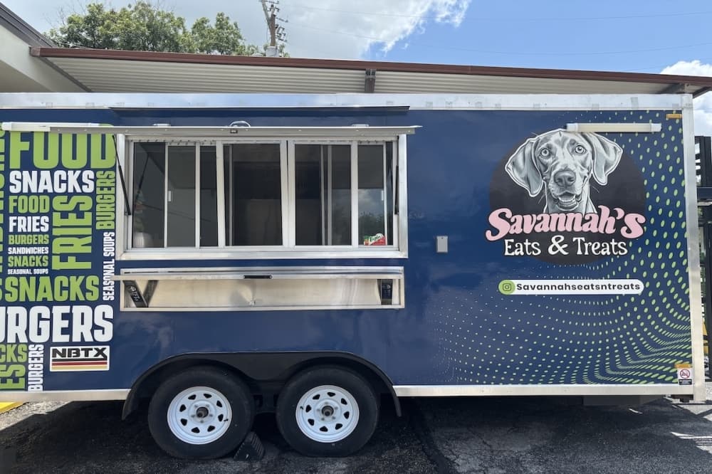 A blue food truck with a large dog imprinted on the logo.
