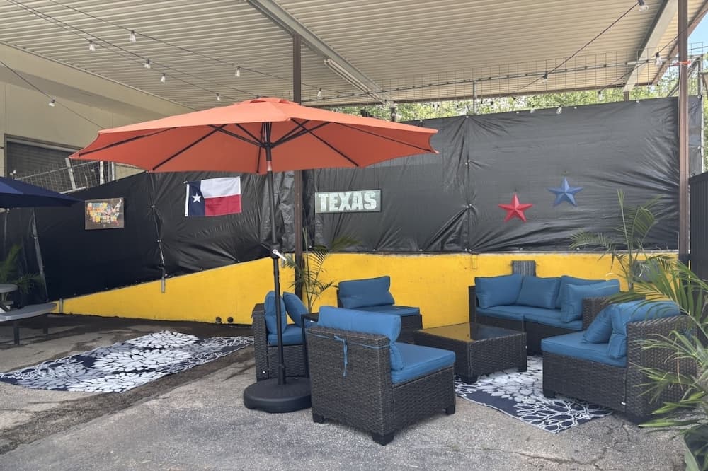 A small seating area with couches, an umbrella, and a Texas flag for decoration.