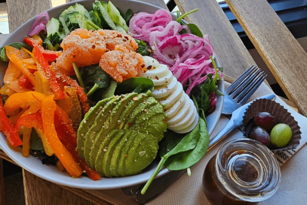 A plated salad with a side of grapes and sauce