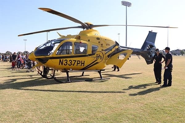 people walk around and look into a helicopter