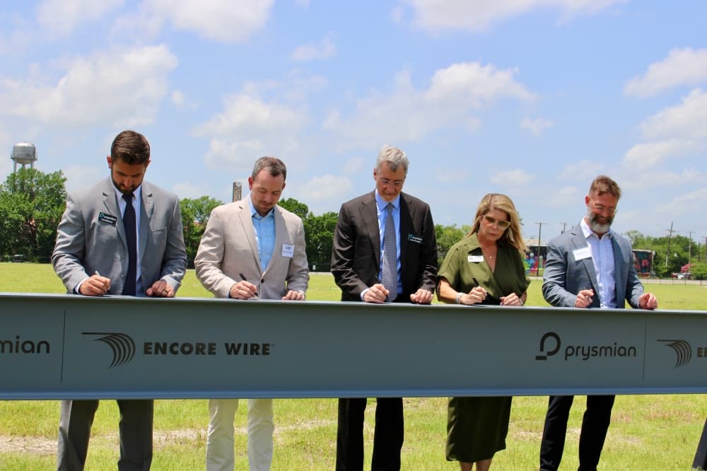 Event attendees signing a commemorative beam
