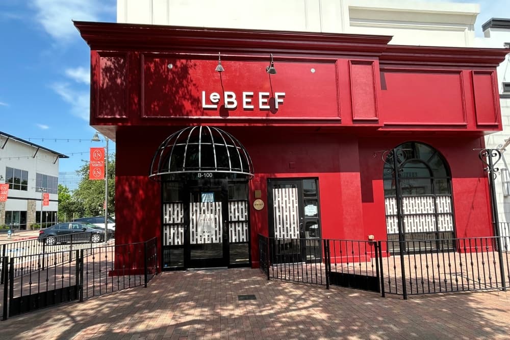 Exterior of a red building with LeBeef signage and patios. 