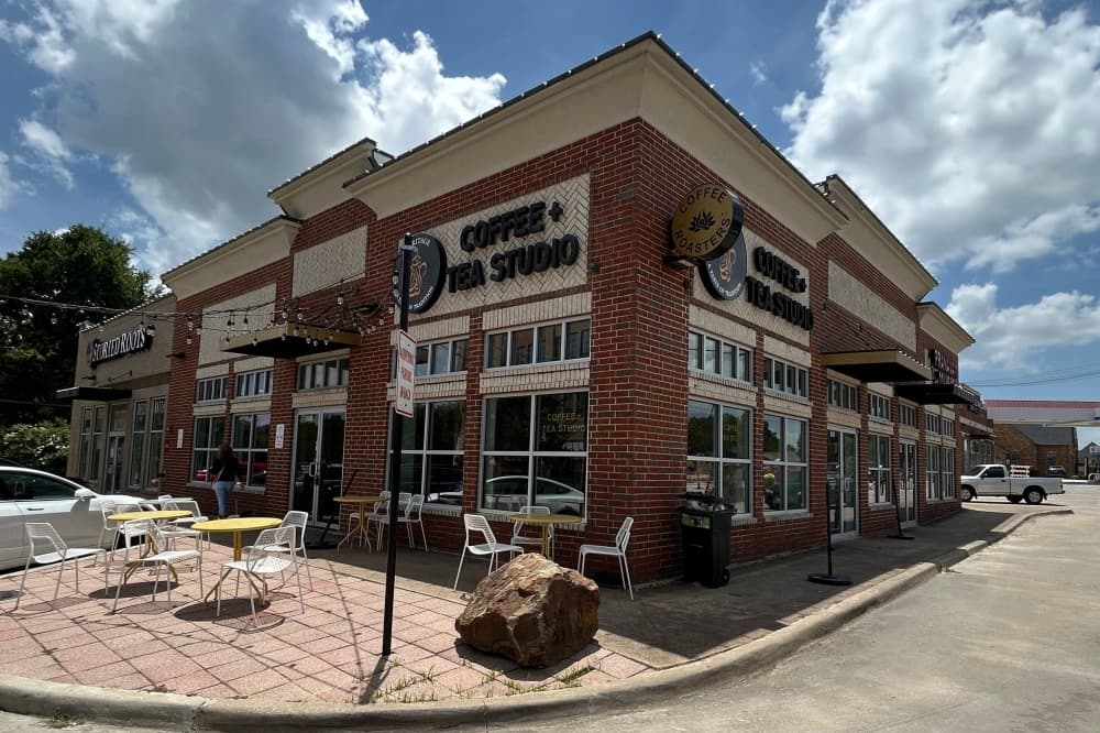 Exterior of a corner spot in a strip mall with Heritage Coffee and Tea signage. 