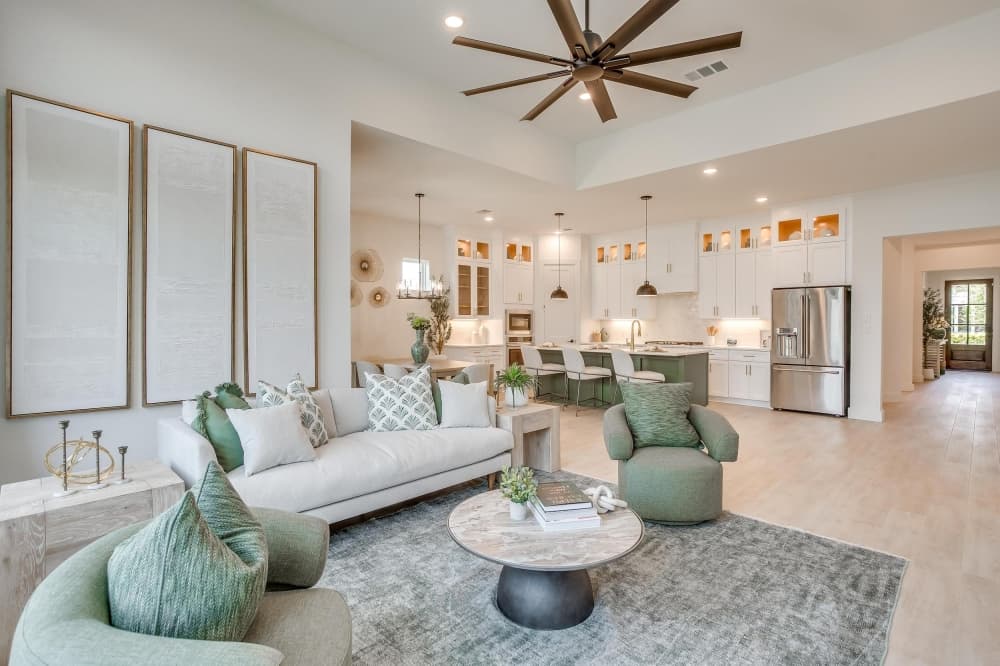 Open-concept living area with hardwood floors and large windows in William Ryan Homes model. 