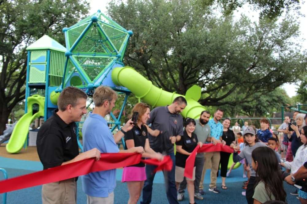 City leaders cut a red ribbon in front of the playground. 