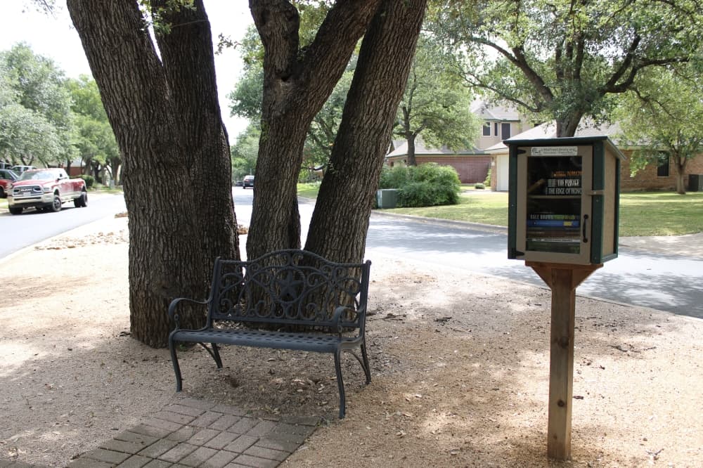 The neighborhood has a little free library and shaded bench. (Anna Maness/Community Impact)