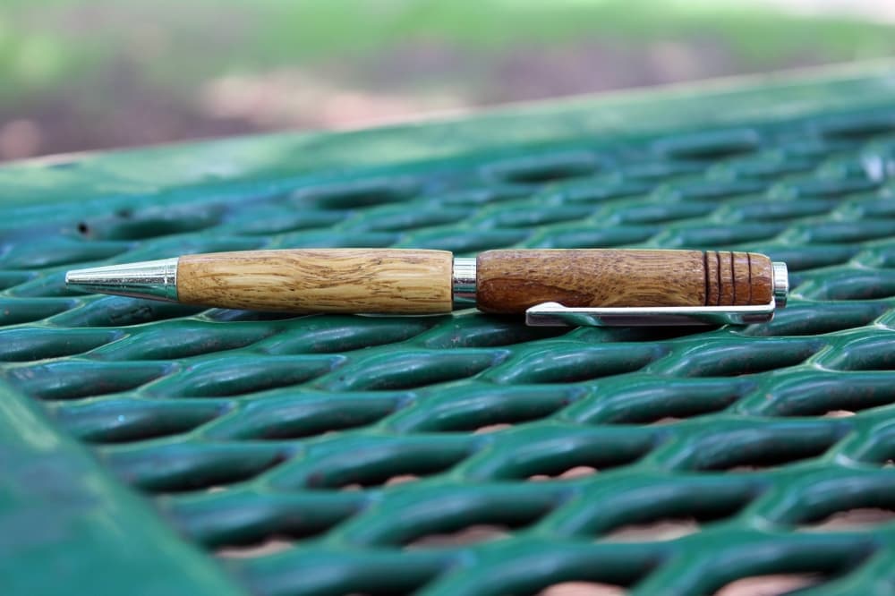 Two-toned wooden pen sitting on a metal park table. 