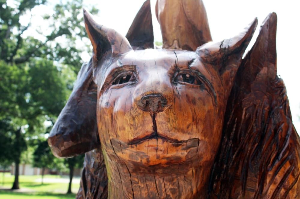 Wood sculpture of a canine in a larger wood sculpture. 