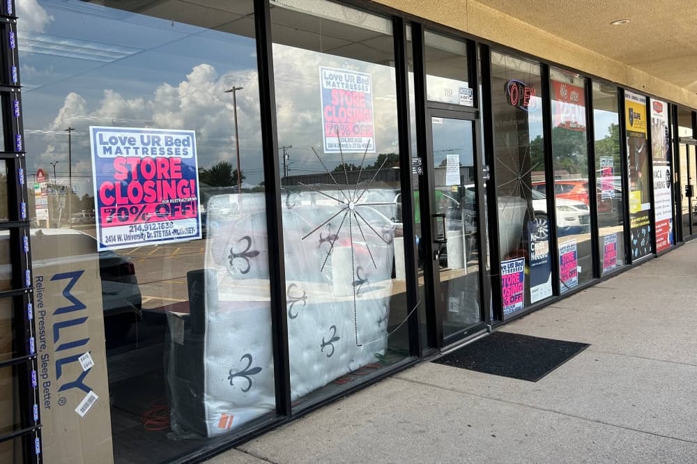 Exterior of strip mall with Love UR Bed store closing temporary signs in store front windows. 