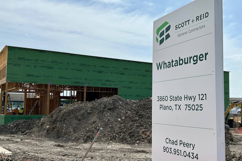 Under construction single-story building behind a temporary sign featuring Scott   Reid Whataburger 
