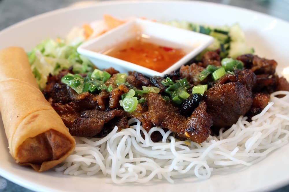 Grilled pork vermicelli ($14.50) features pork, vermicelli noodles, lettuce, bean sprouts, cucumbers, pickled carrots, daikon and scallion oil, served with peanuts and fish sauce. (Karen Chaney/Community Impact)