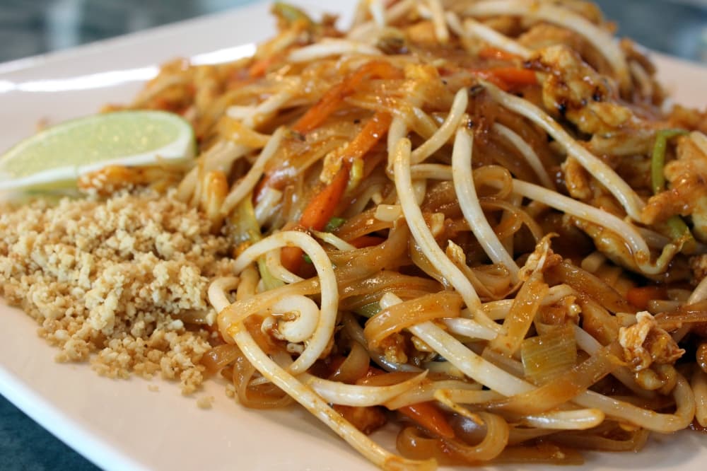 Chicken covered with light brown sauce and bean sprouts with side of crushed peanuts. 