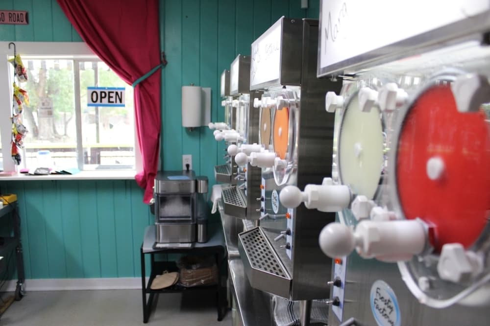 A row of frozen drink machines inside of a beverage making kitchen.