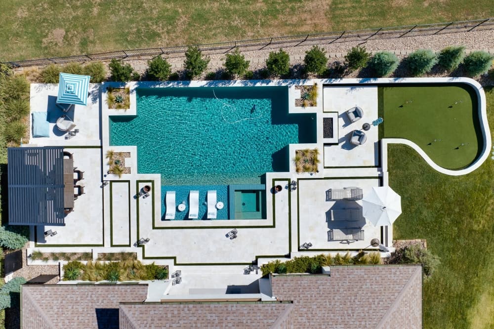 Overview photo of a house with a pool, patio and putting green. 