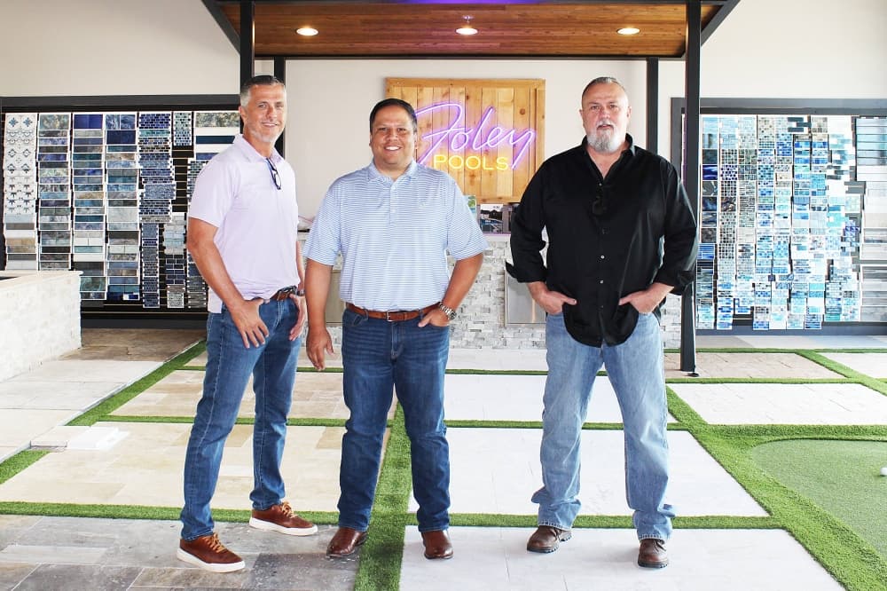 Three males standing in a pool showroom. 