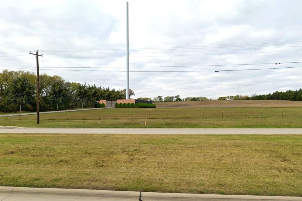 A cell tower with a masonry wall enclosing the tower. 