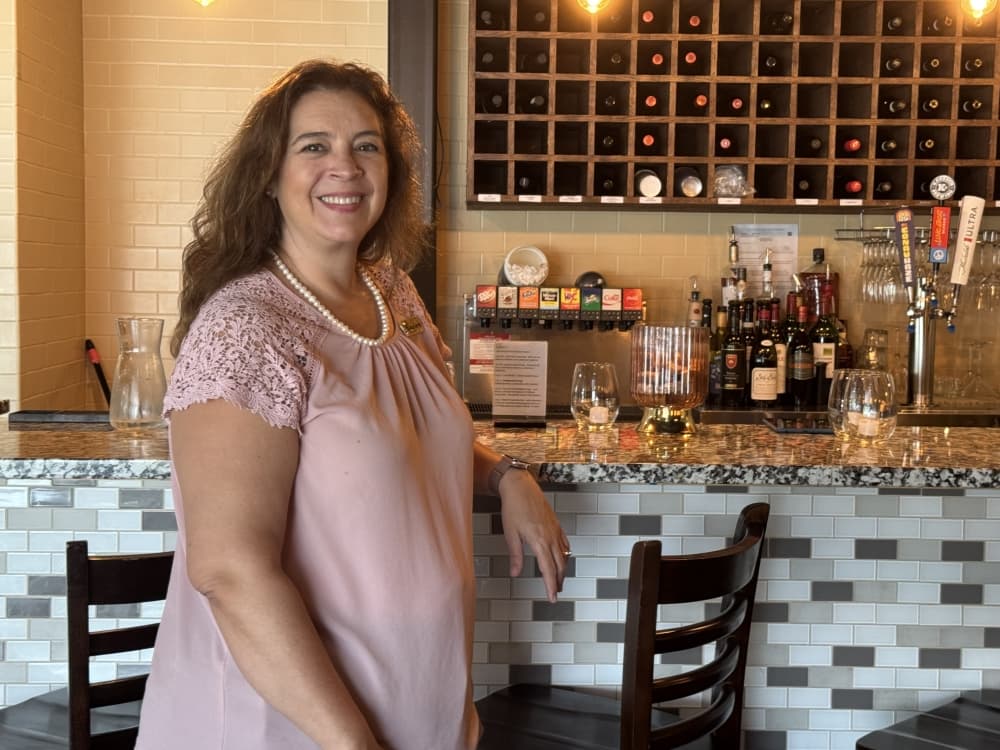 A woman in front of a wine bar. 