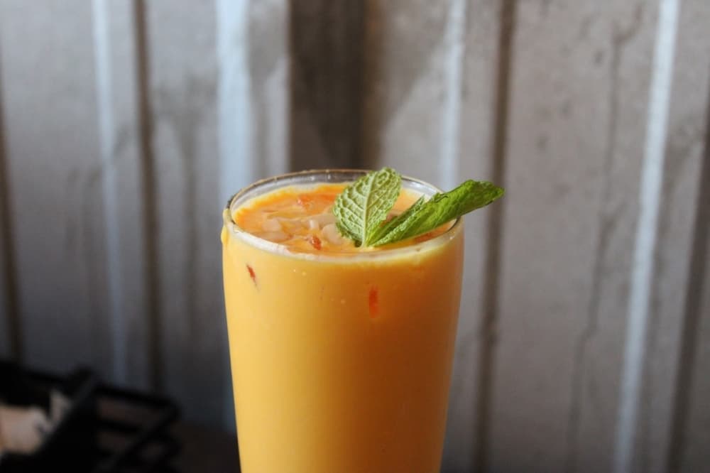 A glass with a smoothie, garnished with mint leaves.
