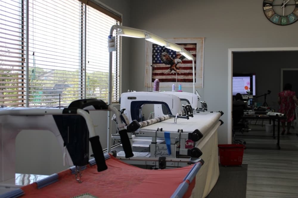 A row of large, long-armed sewing machines made for making quilts and blankets.