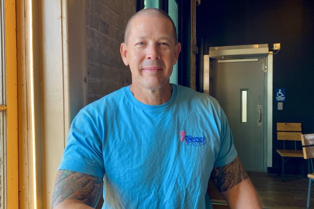Image of Troy Dudley in a blue shirt next to a window at Prost Alehouse 