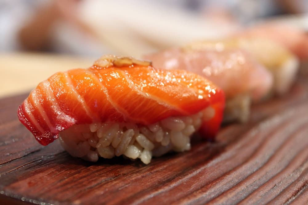 Five pieces of nigiri on a wooden tray.