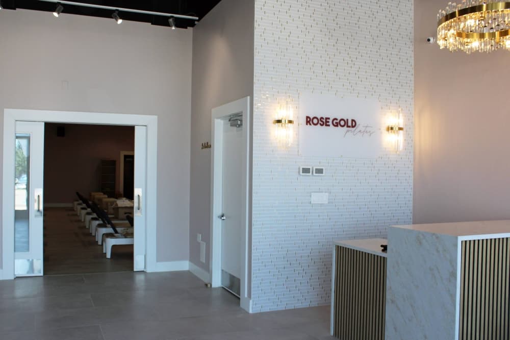 Interior of a business with Rose Gold Pilates signage featuring rose gold color walls.