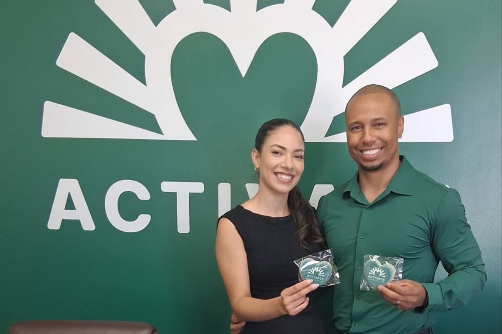 Male and female standing next to each other in front of a wall with Activate branding.